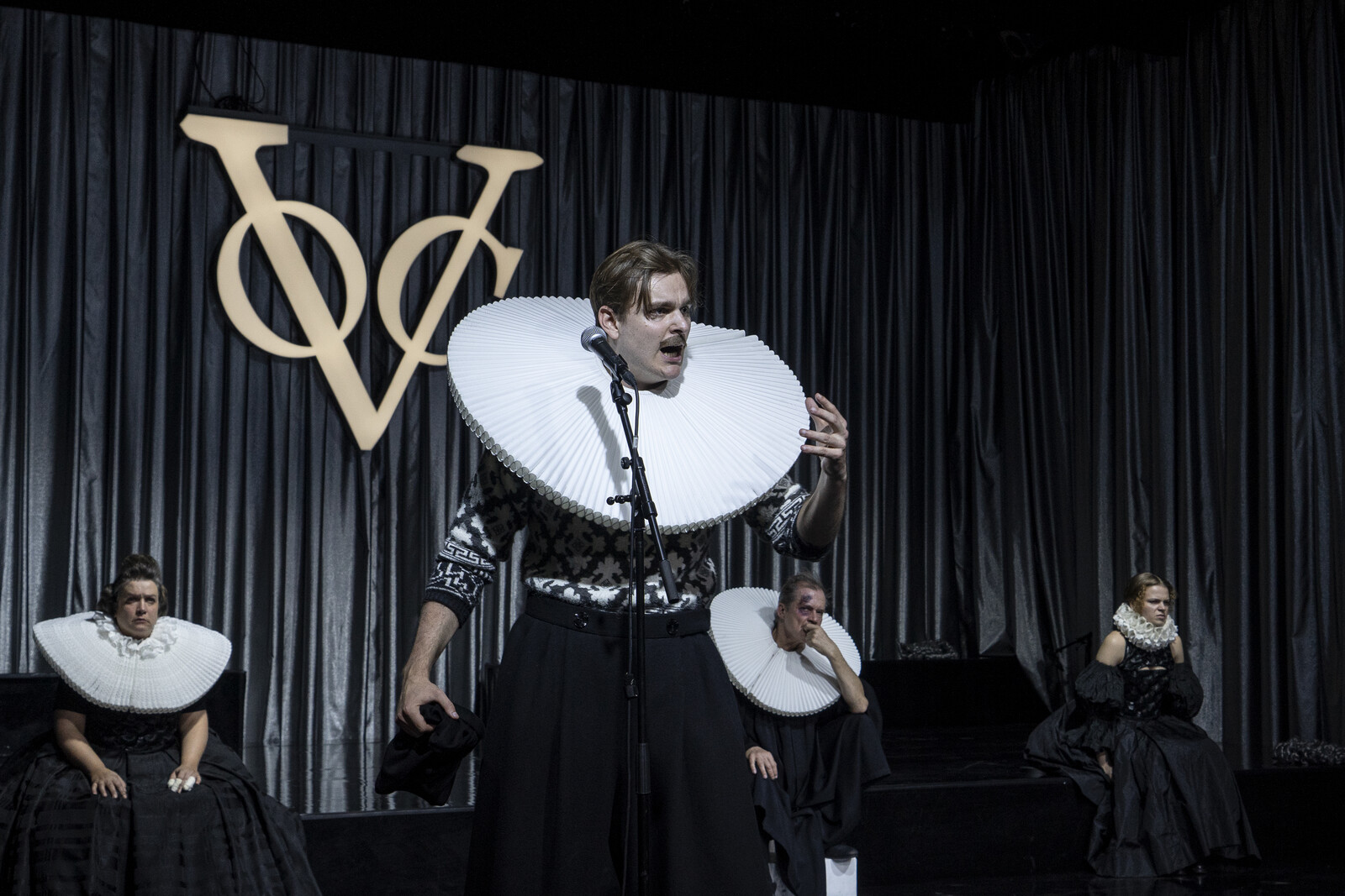 Ruprecht declares at the microphone in front, with Marthe, Adam and Eve sitting in the background.
