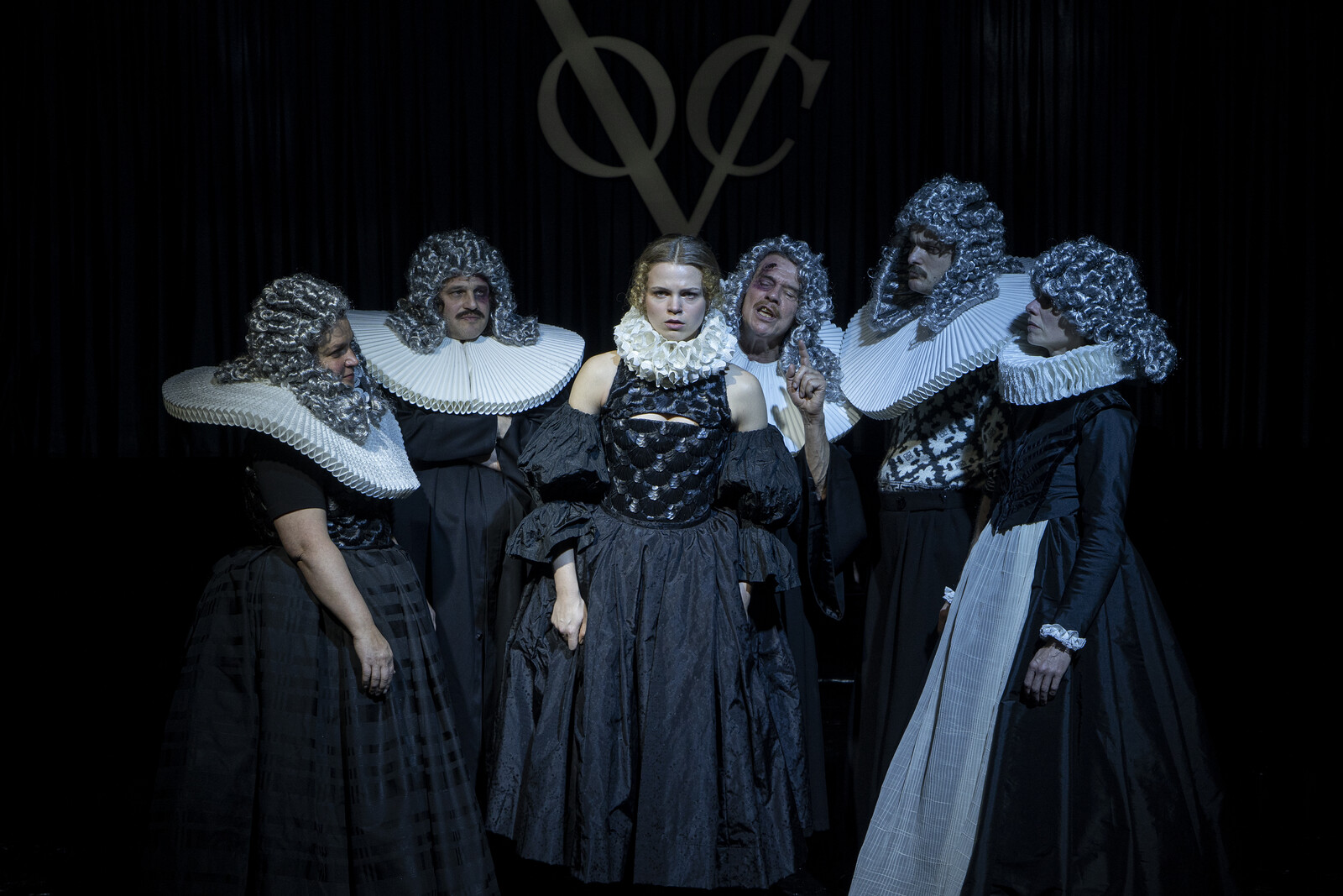 Eve in the centre, surrounded by the village community, all wearing the judge's wig on their heads.