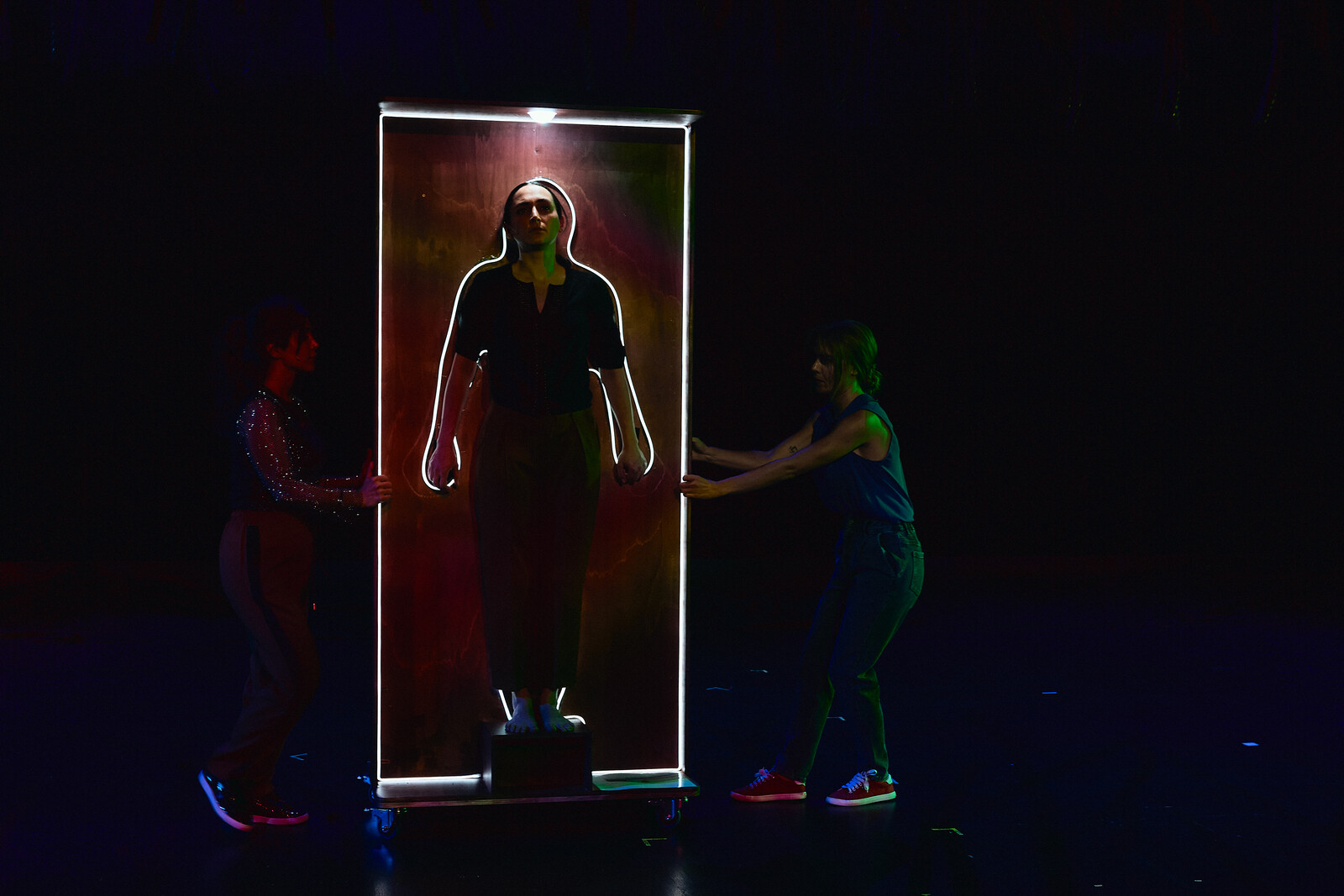 Person hell erleuchtet in einem Rahmen der von zwei Personen gehalten wird