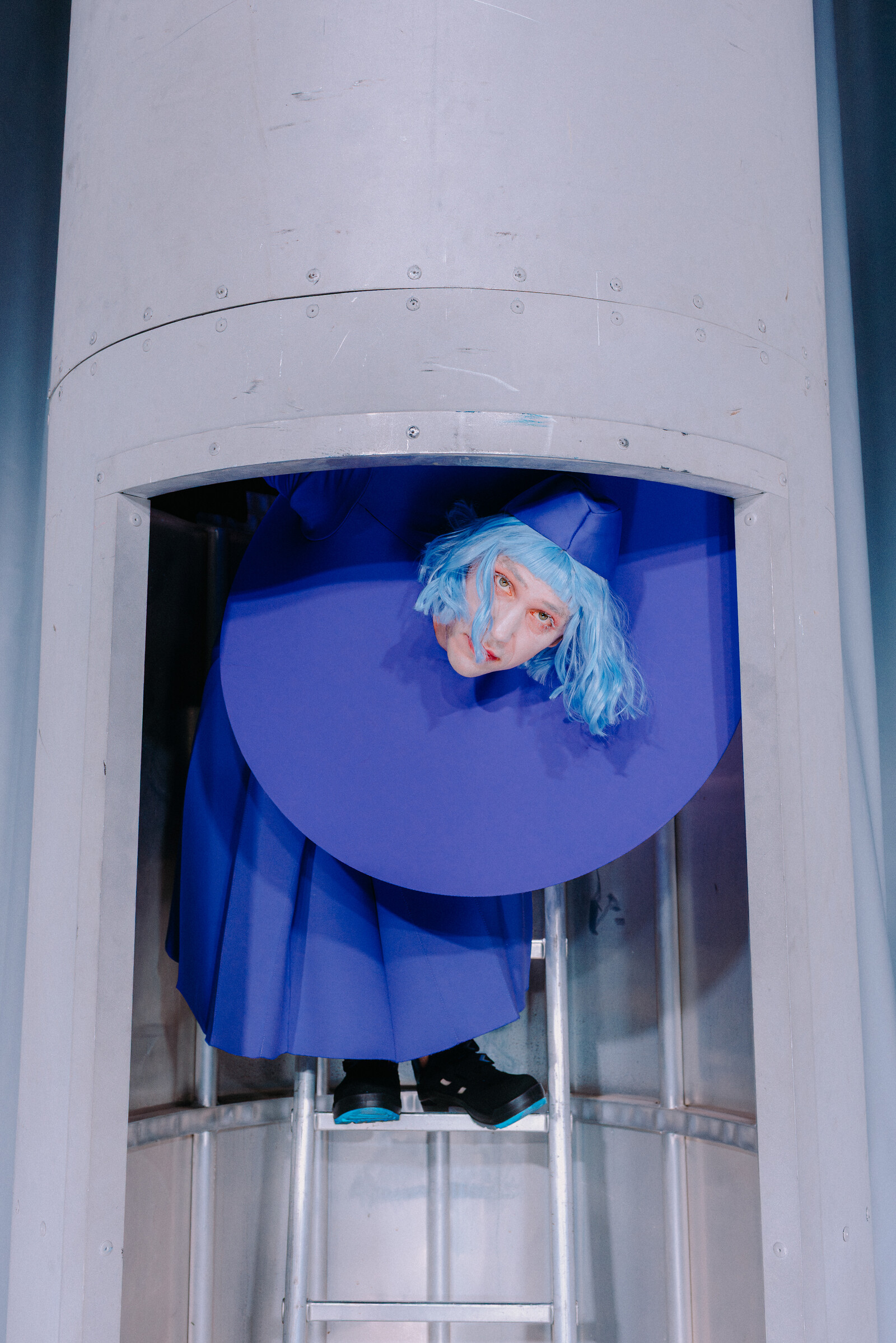 Bernhard Glose peeks out from a silver shaft while standing on a staircase.