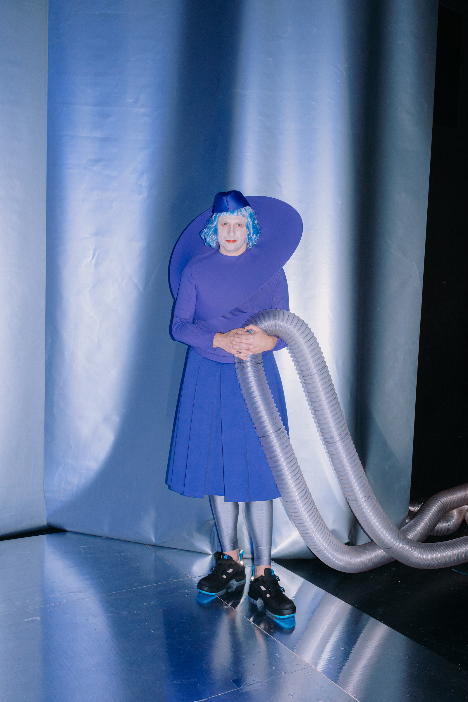 Philipp Plessmann, dressed in a blue suit, is holding a large hose in his hand.