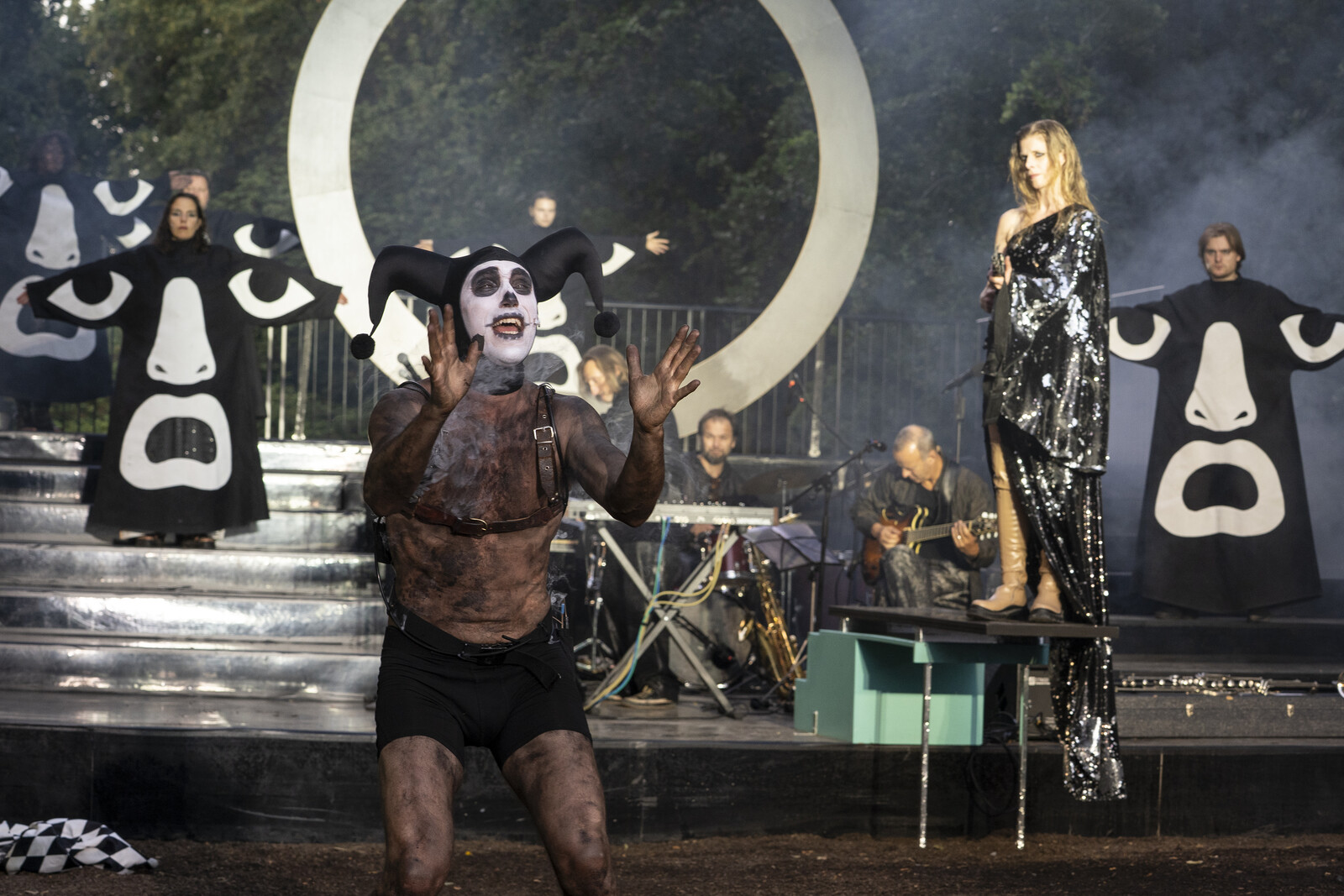 Bernhard Glose, wearing a clown’s face and a jester’s cap, with Dagmar Geppert looming menacingly behind him in a black glittery dress.