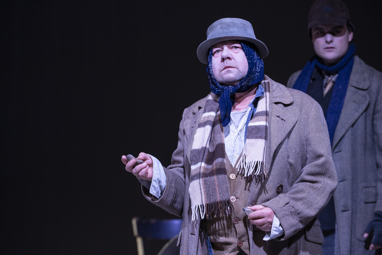 One in the foreground; he is wearing a hat and a coat, and has a scarf wrapped around him