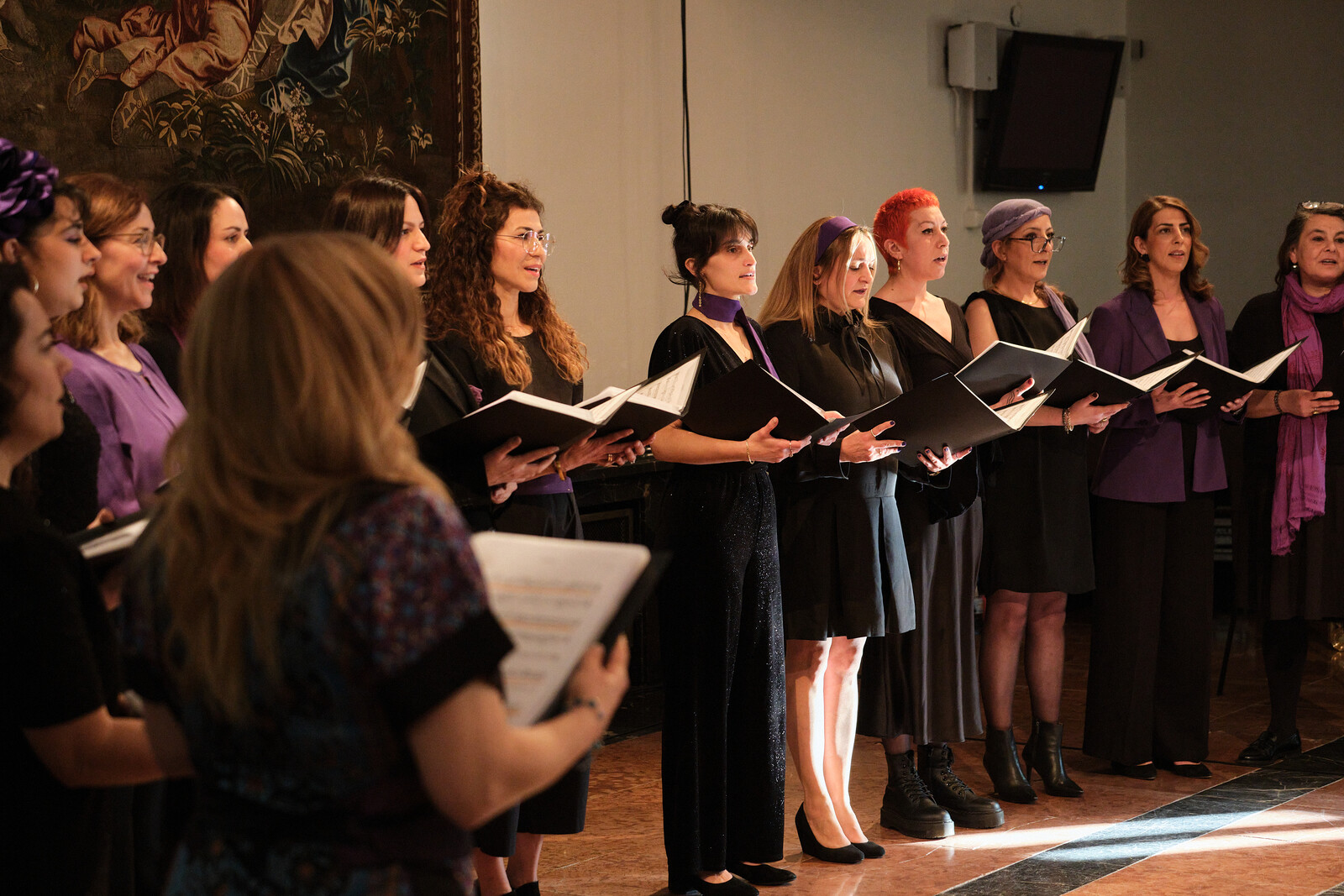 Several women are standing in a semicircle and singing 