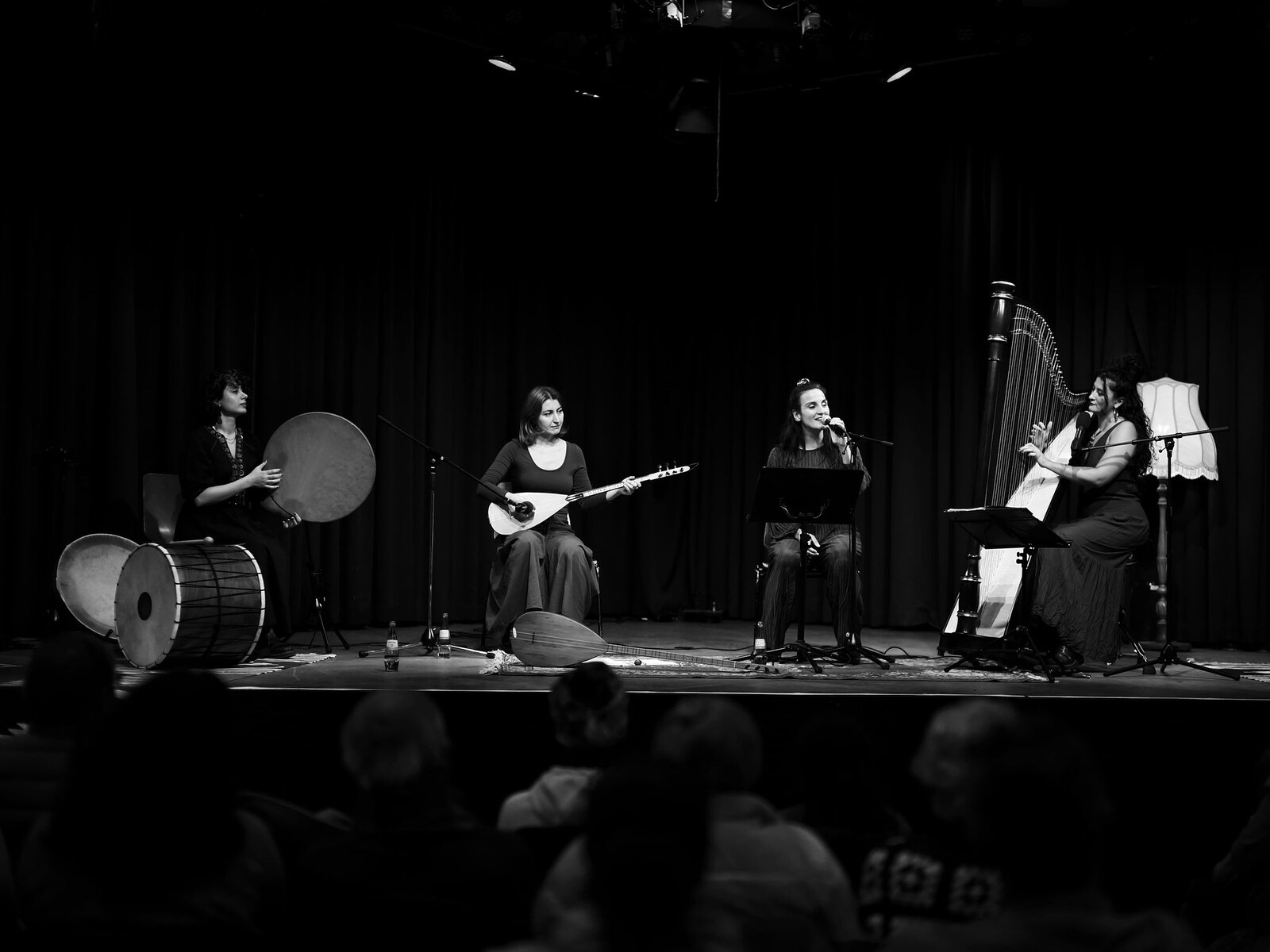 Several women holding musical instruments are standing on a stage 