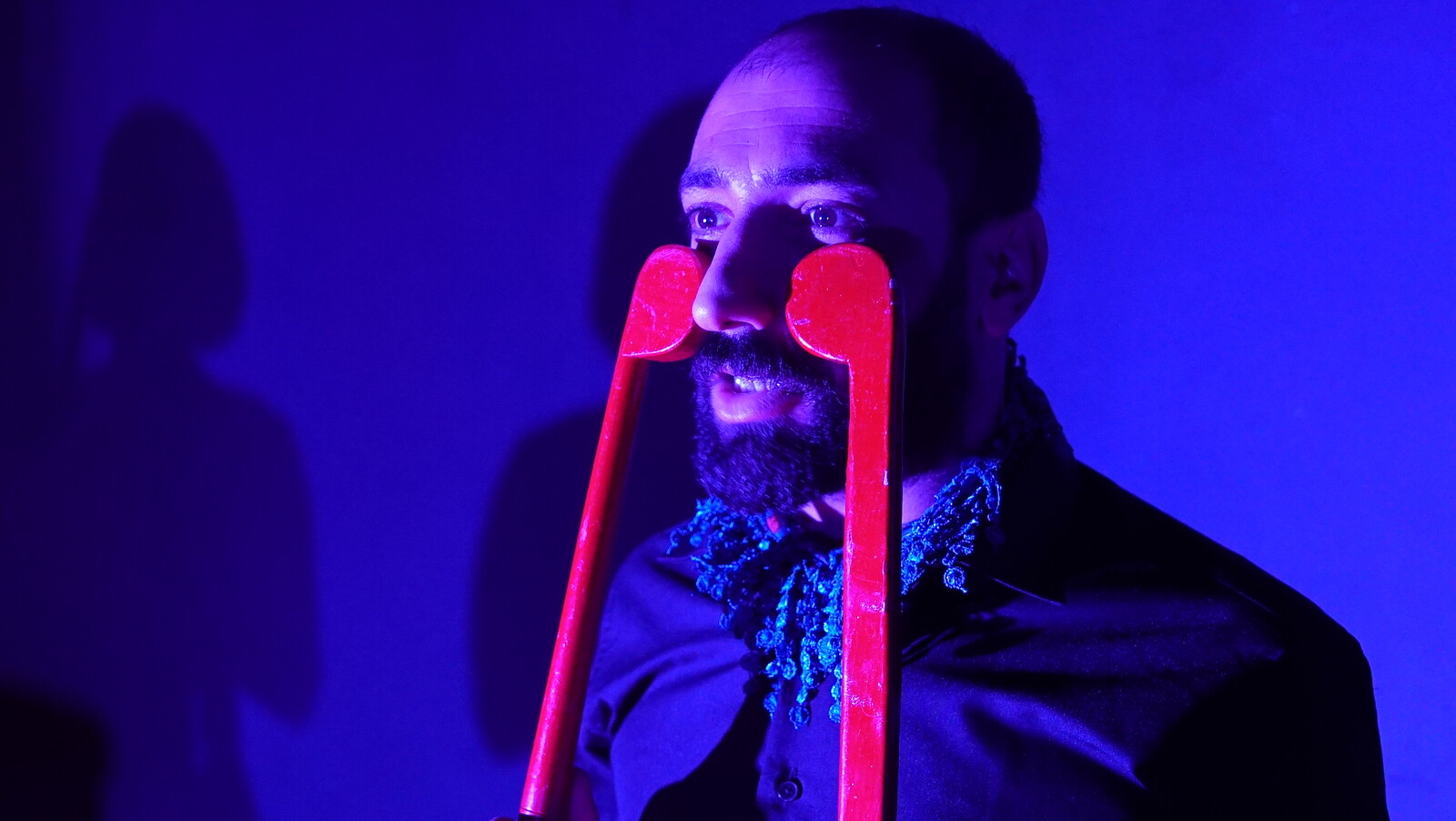 Mann hält sich zwei Stöcke ins Gesicht