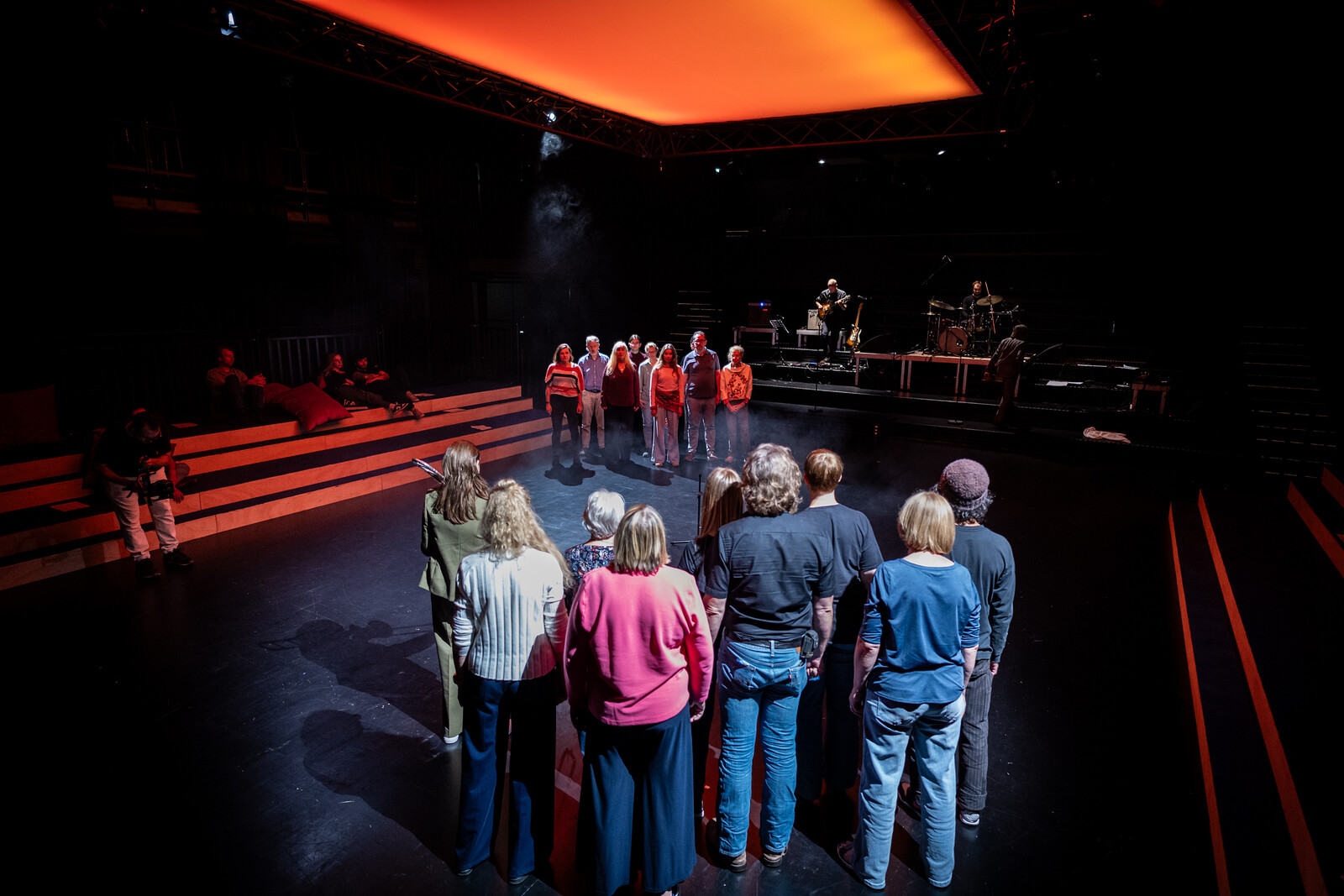 Two groups of people stand facing each other, arguing beneath an orange umbrella.