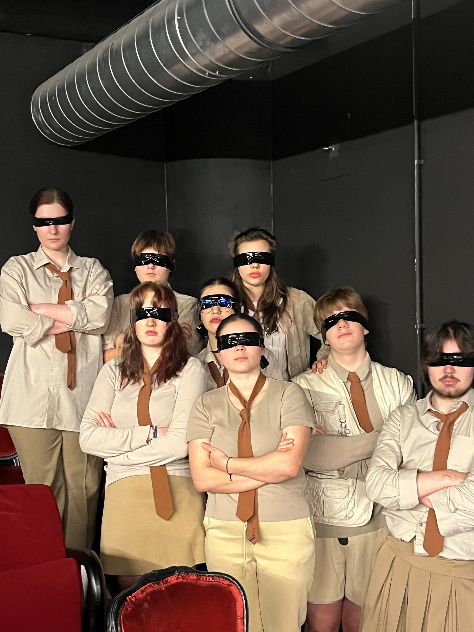 das Ensemble steht mit verschränkten Armen im Zuschauerraum  