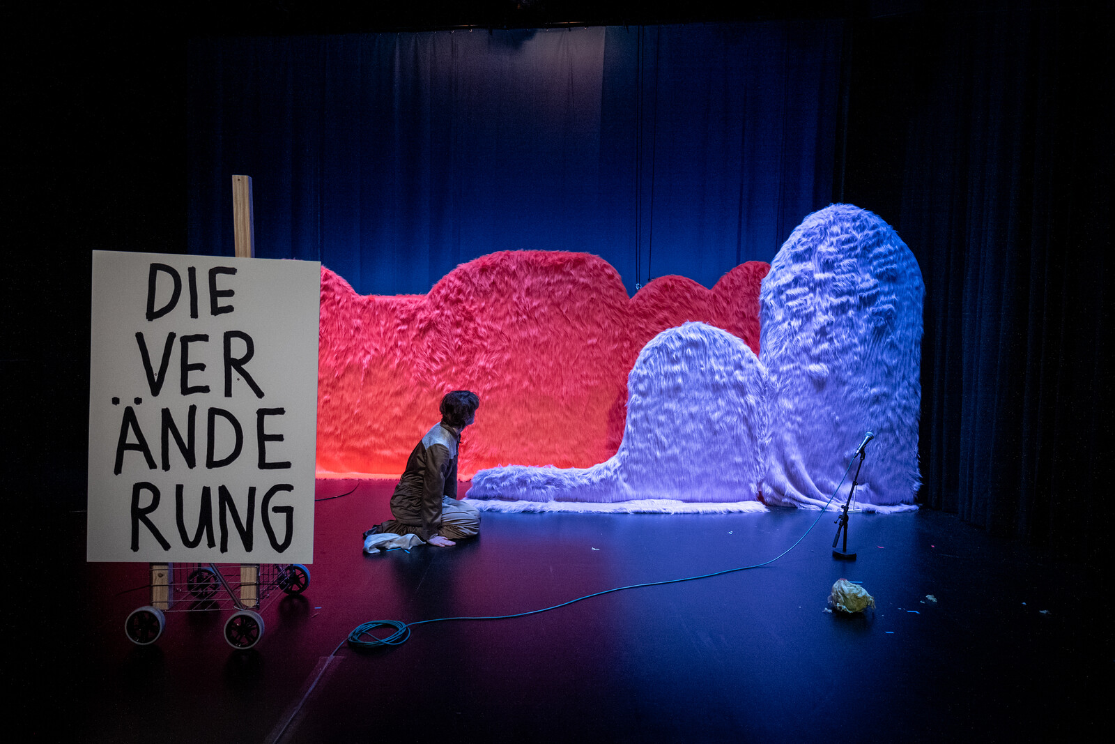 Schauspielerin auf Bühne neben großem Schild auf dem "Die Veränderung steht"