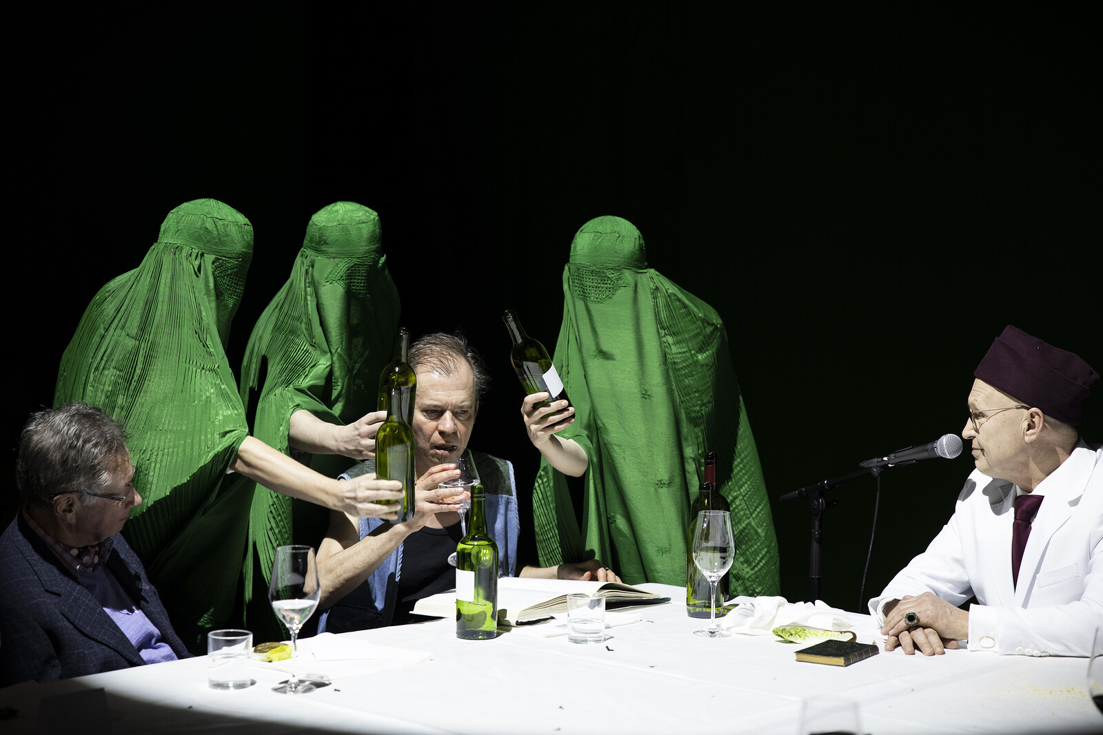 Women in green burkas pour wine