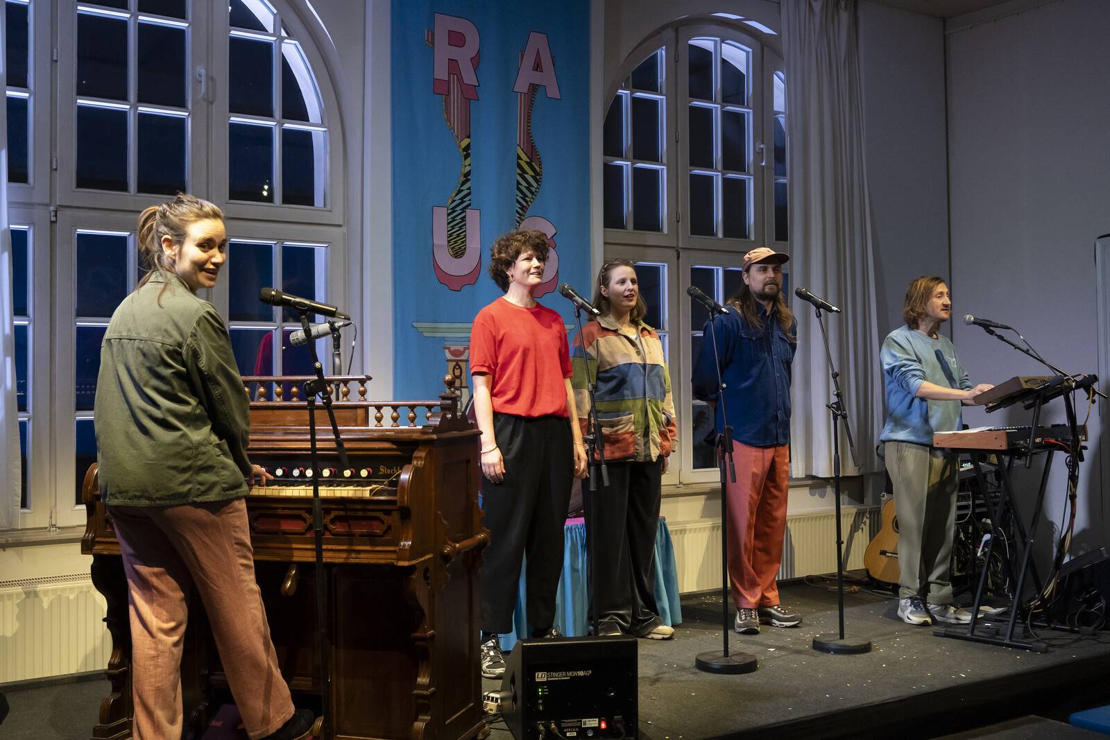 The group subbotnik at microphones and musical instruments on a stage in the foyer.