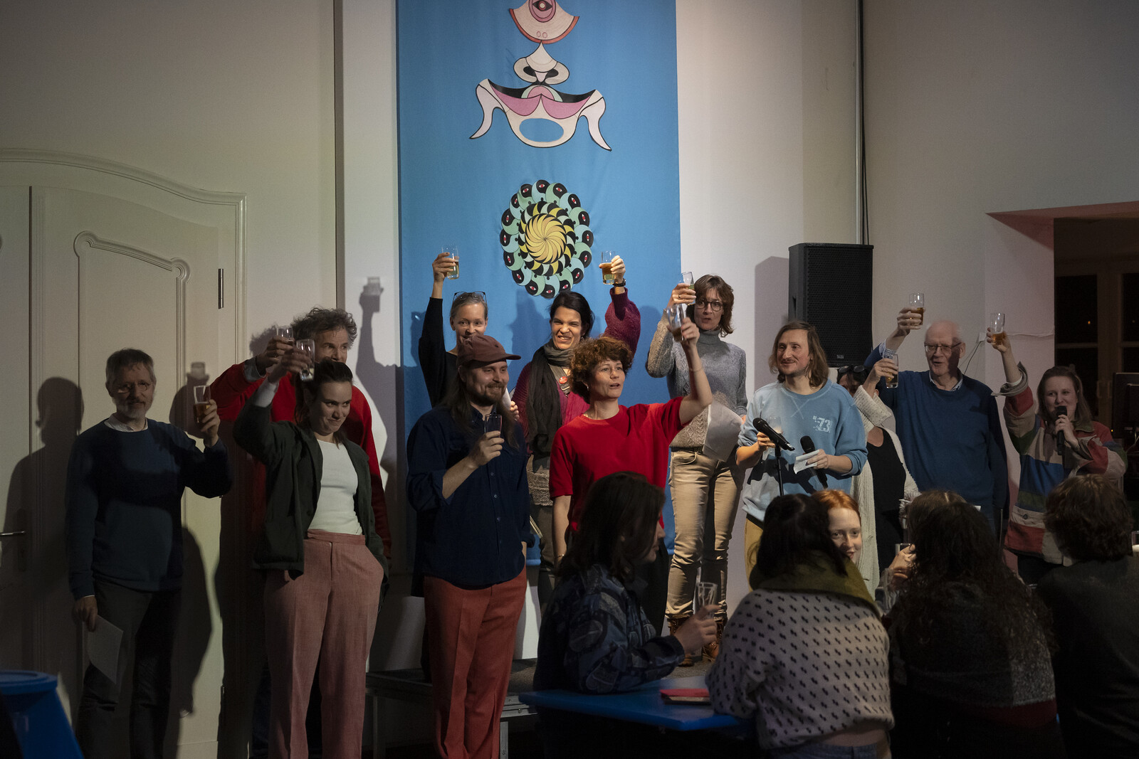 Singers stand on a small side platform and toast each other and the audience.