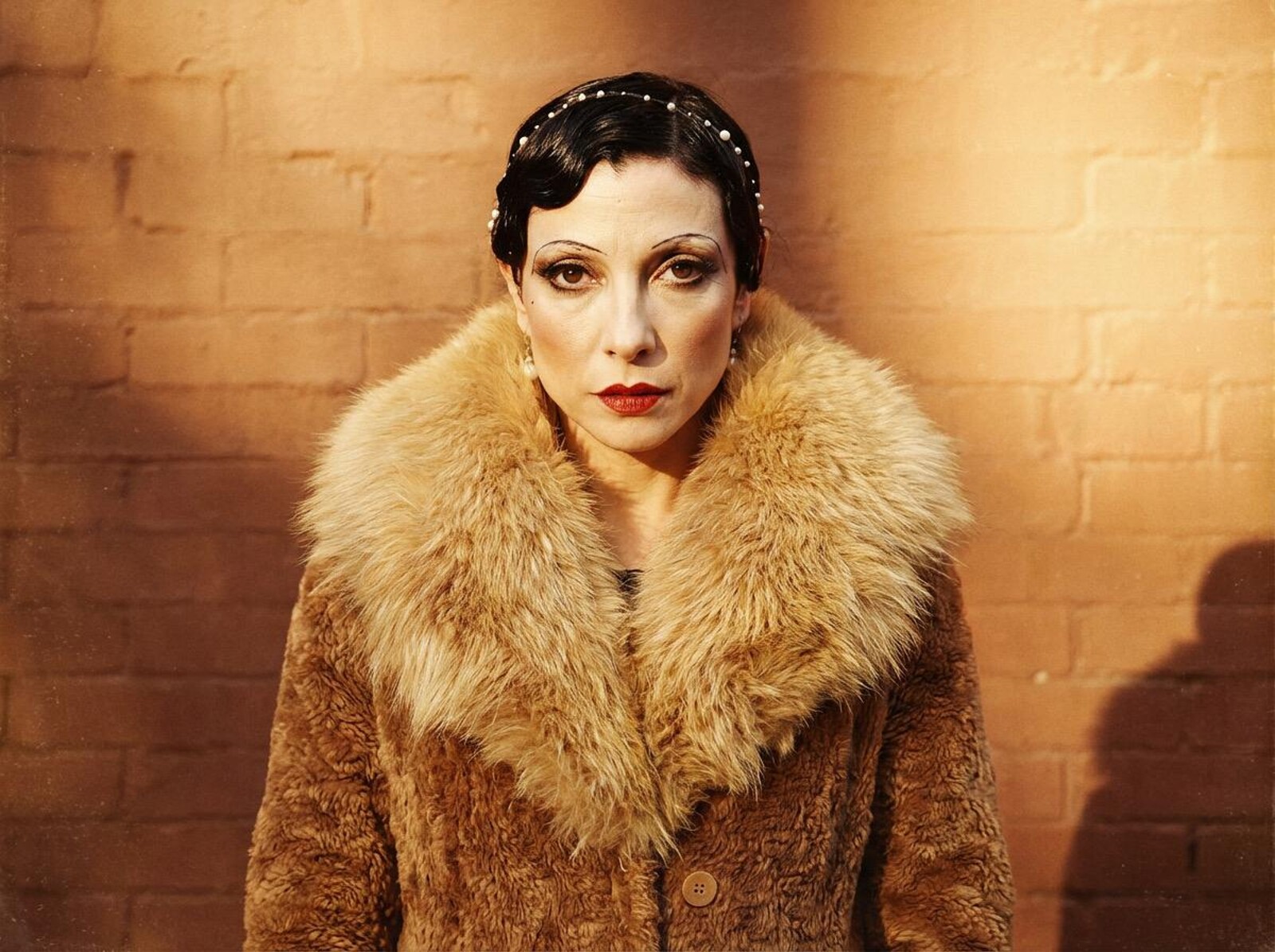 a woman in a fur coat in front of a yellow wall